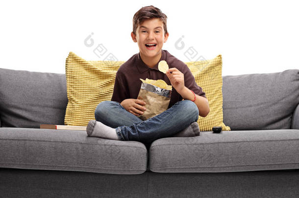 小男孩坐在沙发上吃薯片