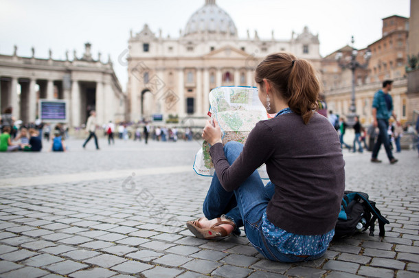 漂亮的年轻女游客学习地图在圣伯多禄广场