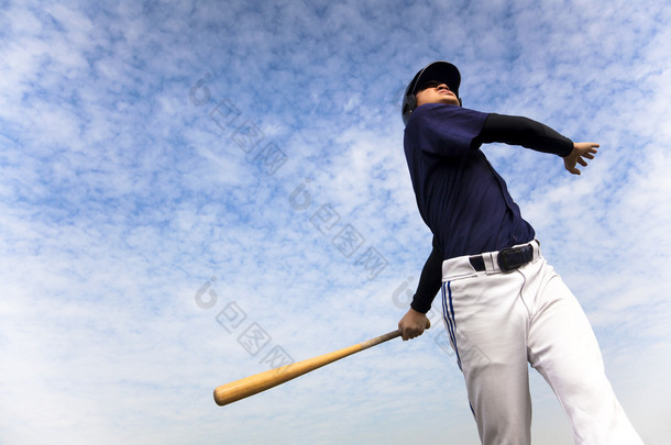 带云彩背景挥杆的棒球选手