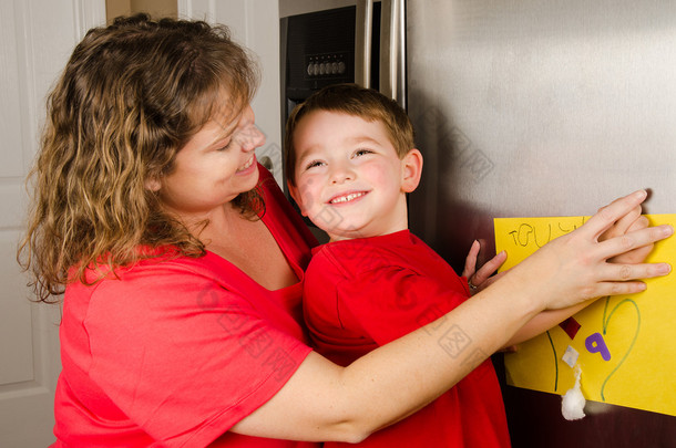 母亲和儿童家庭冰箱在家里上张贴男孩的<strong>艺术</strong>