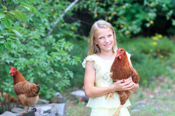 年轻的金发女孩在花园里与她鸡