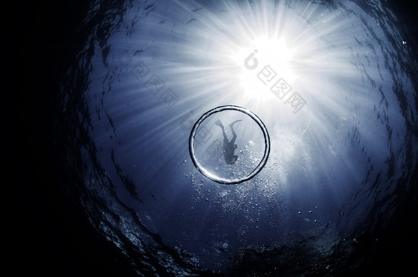 一名潜水员，包围着太阳在他们身后的光束 snell 窗口内的泡沫环