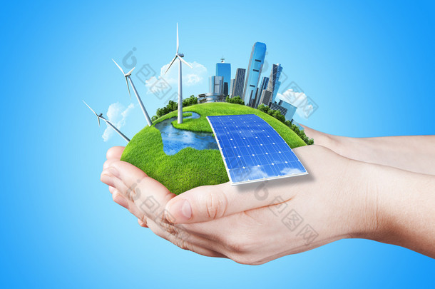 手中持有明确绿色草原与太阳电池块、 磨风力涡轮机和城市<strong>的</strong>摩天大楼
