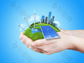 手中持有明确绿色草原与太阳电池块、 磨风力涡轮机和城市的摩天大楼图片