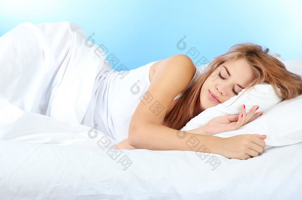 年轻漂亮的女人睡在床上在蓝色背景