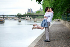 幸福浪漫情侣拥抱附近塞纳河，女孩跳跃