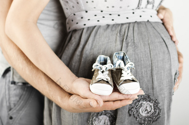 初生婴儿靴在父母手中。关闭.