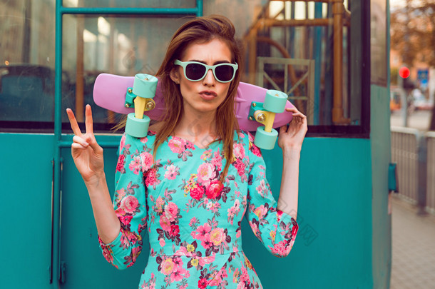 美丽和时尚的年轻女子和一个滑板在城市街道上的合影
