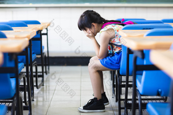 伤心的女孩坐着和思考在教室里 