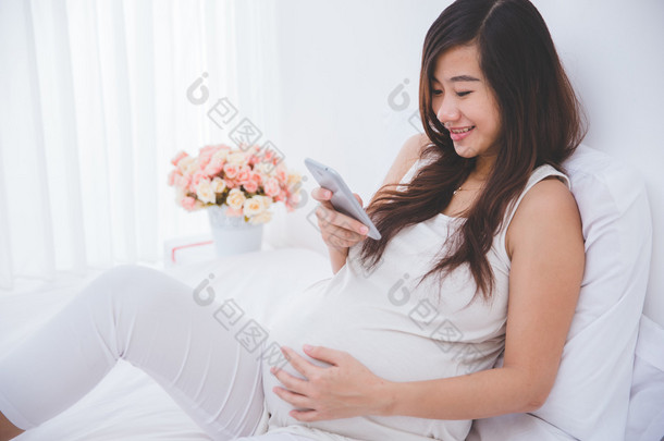 美丽亚洲孕妇使用智能手机