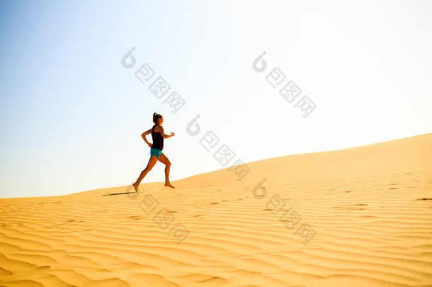 年轻女子在沙漠沙丘上运行