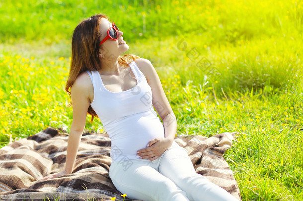 <strong>孕</strong>妇在休息坐在阳光下草地上的太阳镜