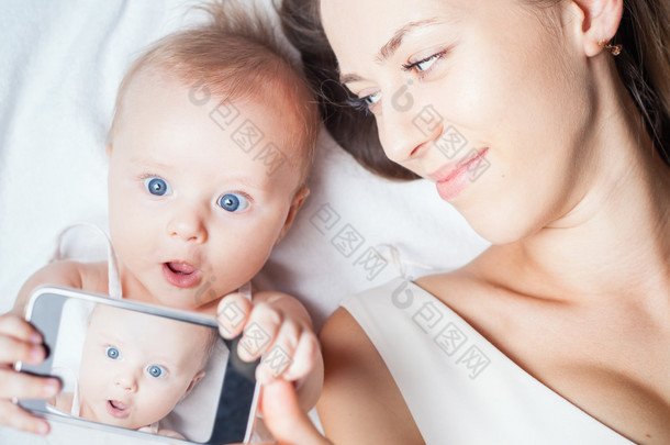 Funny baby girl with mom make selfie on mobile phone