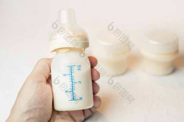 Father holding a baby bottle with breast milk with scale