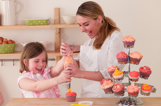 母亲和女儿装饰蛋糕