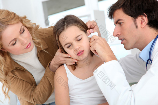 医生看着小女孩的耳朵感染