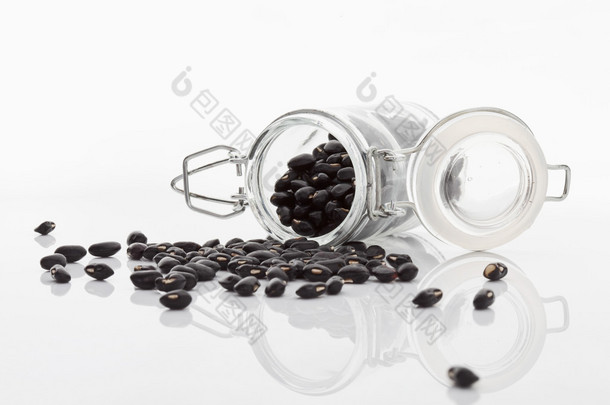 干黑豆洒在白色背景上的玻璃罐子里