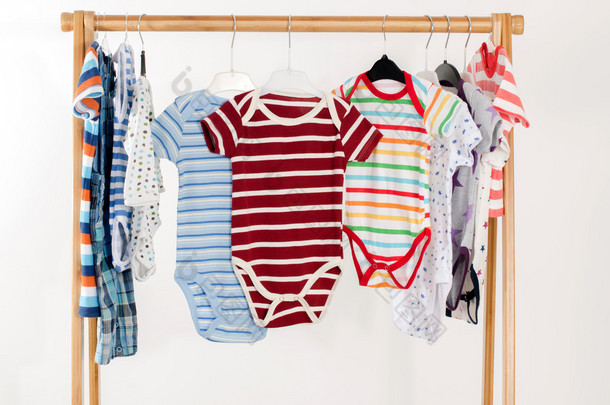 Dressing closet with clothes arranged on hangers.Colorful onesie of newborn,kids, toddlers, babies o