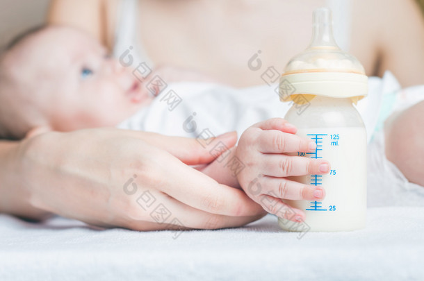 Baby holding a baby bottle with breast milk