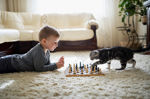 小男孩玩象棋躺在地板上