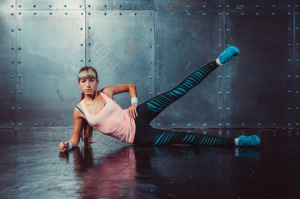 athlete woman exercising warming up and stretching lying on her side the floor with  leg raised conc