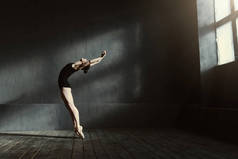 灵活的芭蕾舞演员伸展在黑暗的光线工作室