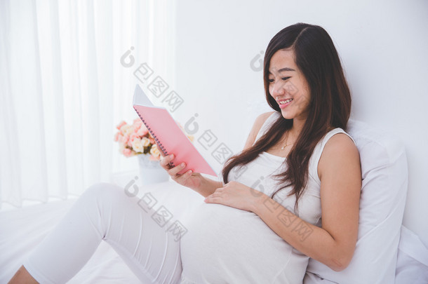 美丽亚洲孕妇阅读<strong>笔记</strong>书，微笑