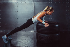 女运动员。健康运动运动员女人做推 ups 对轮胎强度力量训练概念运动量来找到健身锻炼运动和生活方式侧视图
