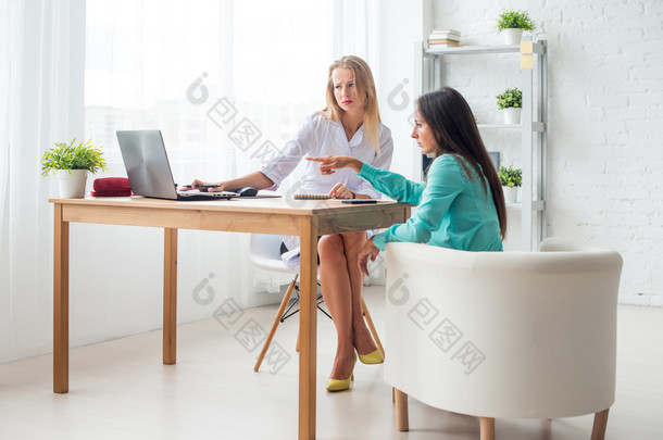 Doctor using notebook to inform patient showing results on computer in office.