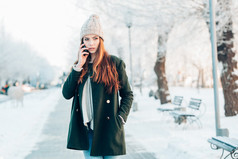 年轻女子微笑着与智能手机和冬季景观.
