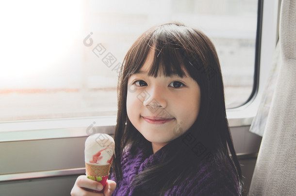小小的亚洲女孩微笑着，吃冰激淋