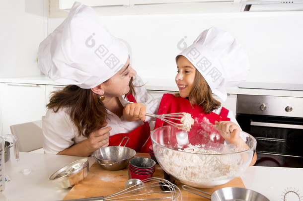 <strong>happy</strong> mother baking with little daughter in apron and cook hat with flour dough at kitchen