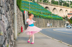 Outdoor portrait of a cute little girl of 7 years old, walking to dance school and dancing in the st