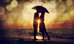 夫妇在日落在海滩伞下的亲吻。o 中的照片