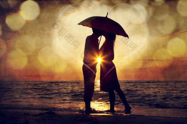 夫妇在日落在海滩<strong>伞下</strong>的亲吻。o 中的照片
