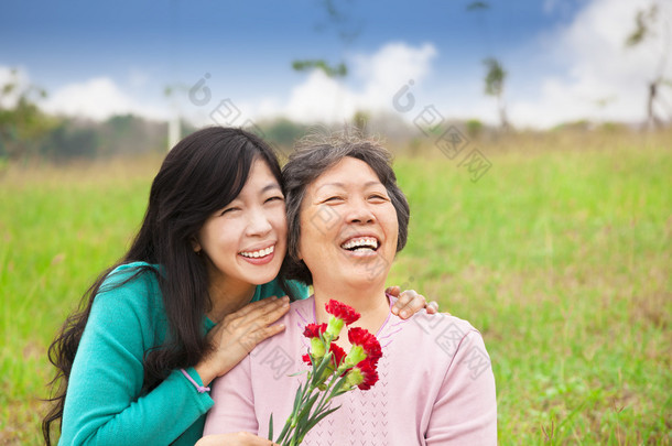 微笑的<strong>女儿</strong>和她的妈妈和香石竹花上 gra