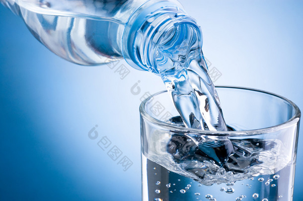 <strong>倒水</strong>从瓶子变成蓝色背景上的玻璃