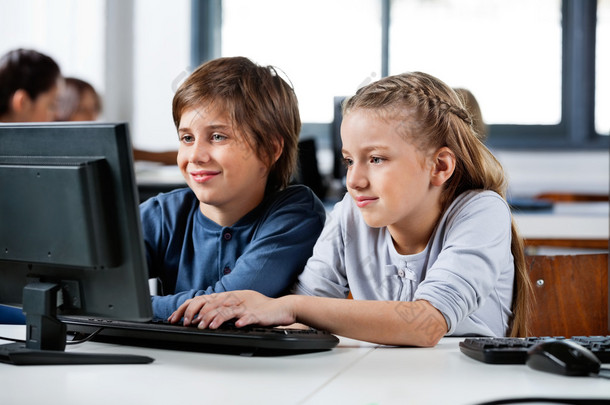 男孩和<strong>女孩在</strong>学校的计算机实验室中使用桌面 pc