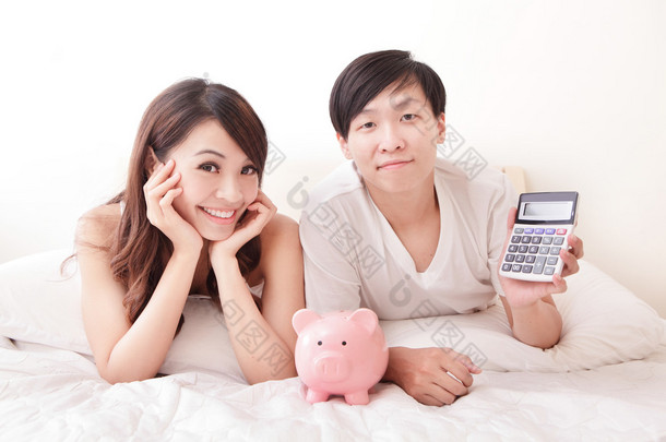 幸福的情侣与粉红猪存钱罐和计算器