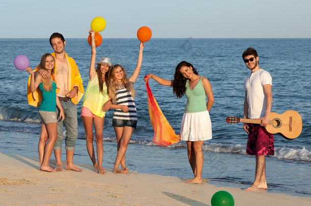 群年轻人享受海滩党与吉他和气球
