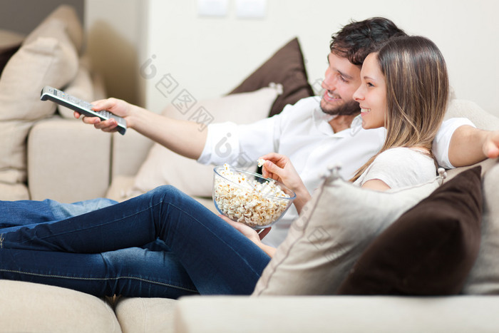 在沙发上看电视的年轻夫妇