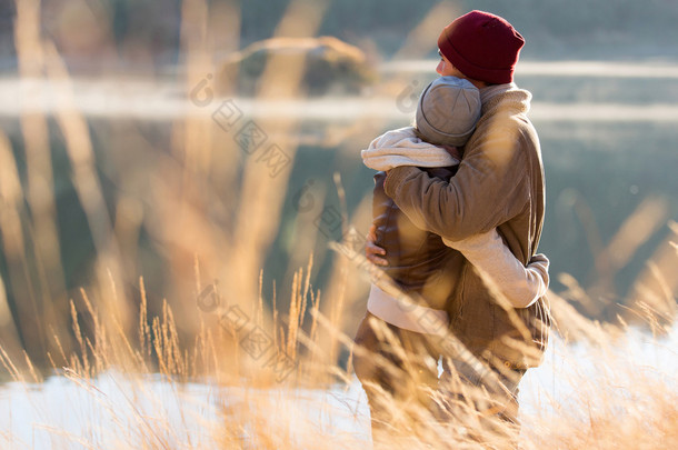 后视图的年轻夫妇在冬季中拥抱