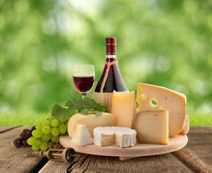 木制的桌子上奶酪板、 葡萄和红酒