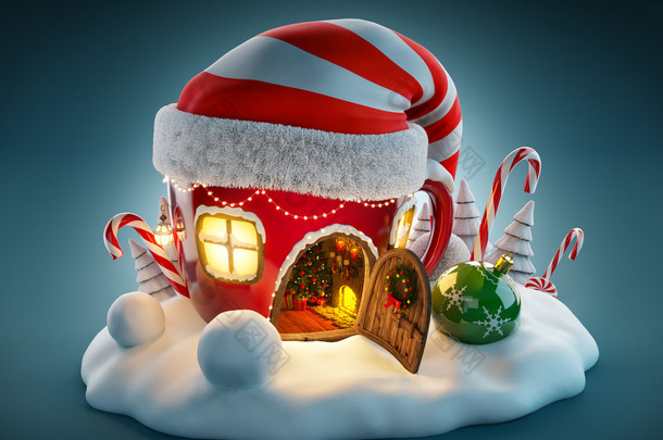 令人惊奇童话房子在 elf 帽子在圣诞节装饰在打开的门与壁炉里面的茶杯子的形状。不寻常的圣诞图.