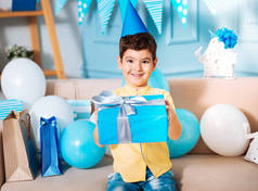 微笑的生日男孩摆在沙发上的礼品盒