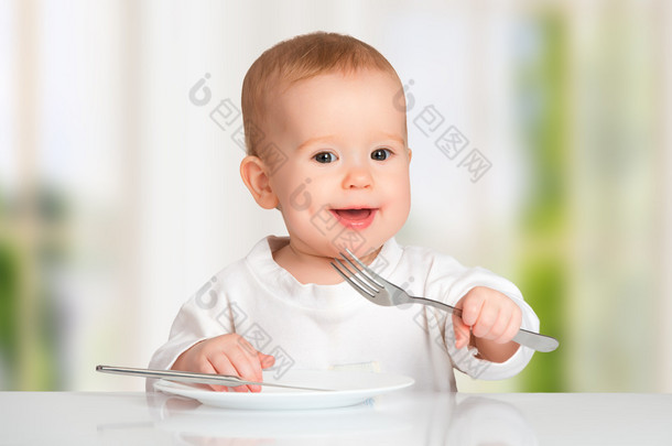有趣的婴儿用刀叉<strong>吃</strong>的食物