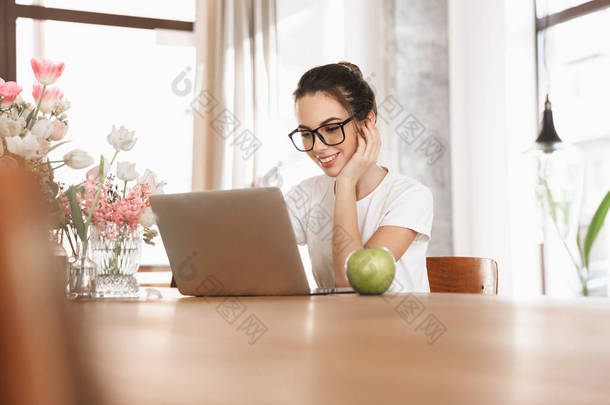 美丽的年轻学生女孩坐在<strong>室</strong>内使用笔记本电脑.