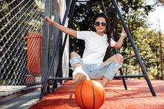 一位可敬的年轻女子身穿休闲的现代服装，在体育场打篮球.