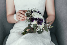 新娘在白色礼服的部分看法与美丽的新娘花束休息在扶手椅
