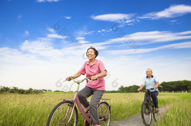 快乐亚洲老人老年人夫妇在农场骑自行车